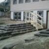 Different angle. Shows new treated lumber staircase installed to allow for movement from above to pathway below. Staircase is free standing and raised just above wall surface.